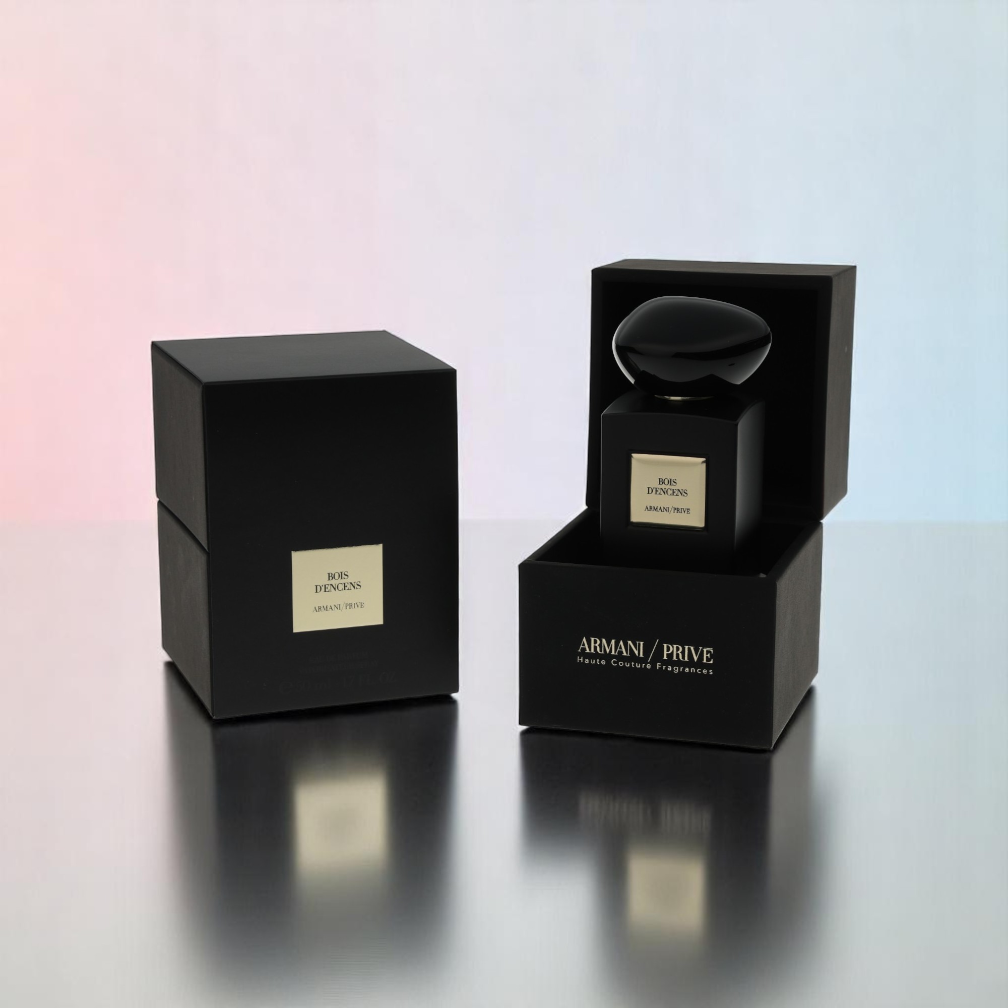 Et pakkebillede af parfumeflasken med dens emballage står på et bord, der afspejler dele af genstandene.